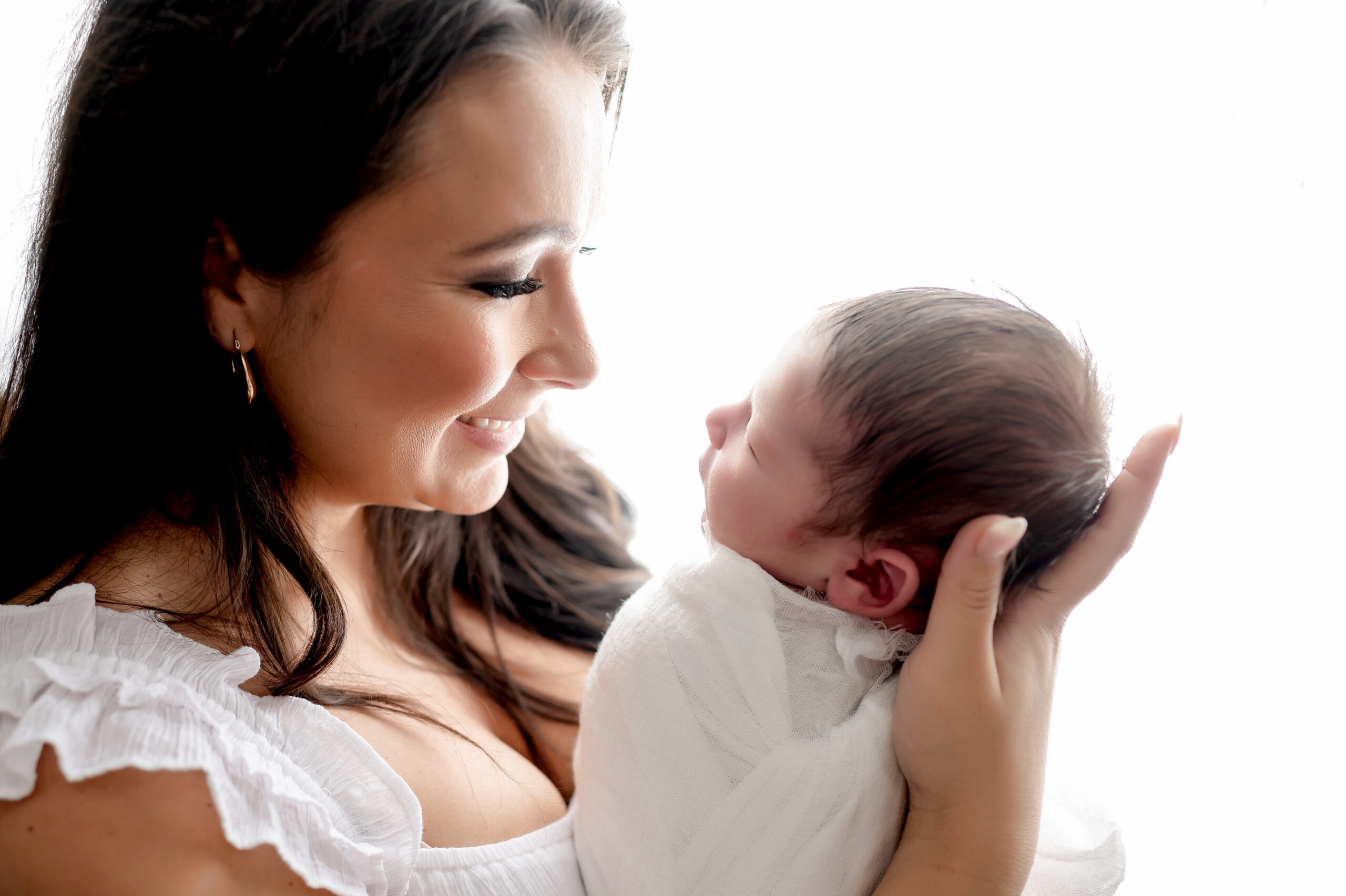 mother looking lovingly at newborn baby boy with lots of hair • Baby