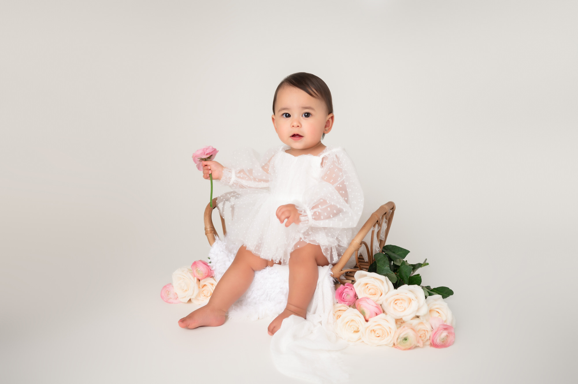 one year old in white dress studio photography surrounded by flowers • Baby